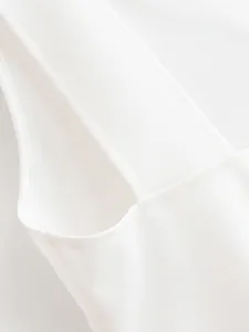 Close-up view of the fine stitching and high-quality white fabric on a halter dress