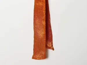 Close-up detail van de oranje gekreukte zijden satijnen stof met elegante textuur.