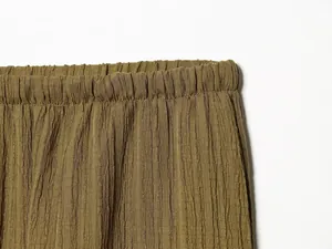 Detail view of the elasticated waistband and crinkled texture on wide-leg trousers