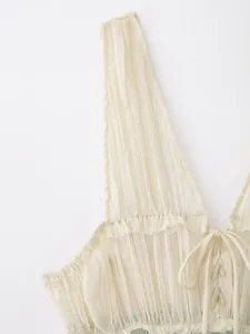Detail van een gebroken witte geplooide top met ruches en veters aan de voorkant