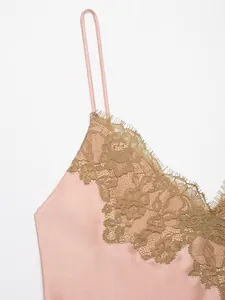 Macro view of intricate gold floral lace and pink satin fabric on a dress.
