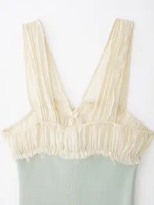 Gedetailleerd zicht op geplooide crème chiffon halslijn en mintgroene ribgebreide top