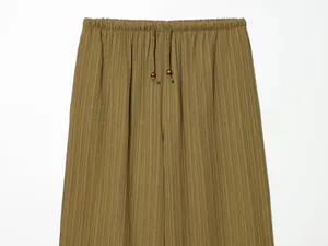 Close-up detail of olive green textured wide-leg trousers with elastic drawstring waist.