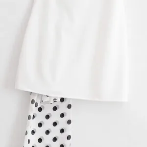 Elegant white halter neck dress featuring a chic black and white polka dot scarf detail.