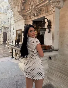 Elegante minivestido blanco con lunares negros lucido por una modelo en un entorno