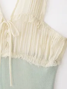 Detail van een patchwork top van geplooid chiffon en geribde gebreide stof met veters