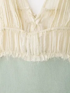 Detailopname van een patchworktop van geplooid chiffon en een geribbelde textuur.