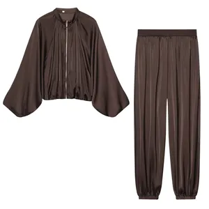 Detailed macro view of the luxurious dark brown satin bomber jacket and harem pants set