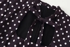 Primer plano de un vestido negro de lunares con lazo en el cuello y cremallera