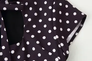 Detalle de primer plano del estampado de lunares blancos en un vestido oscuro retro.