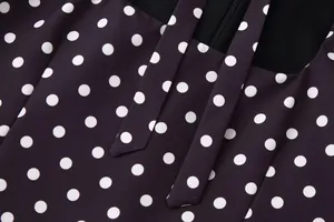 Primer plano del elegante estampado de lunares blancos y detalle de lazo en vestido negro