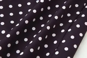 Primer plano de tela con patrón clásico de lunares blancos sobre fondo oscuro