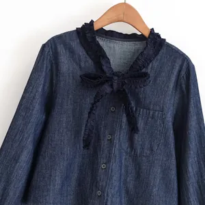 Gedetailleerde weergave van marineblauwe denim blouse met ruffelkraag en strikdecoratie