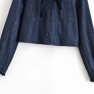 Detail van een donkerblauwe denim korte top met stijlvolle ruches en een borstzakje.