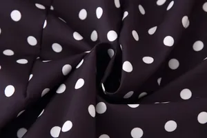 Detalle de primer plano de tela negra suave con estampado de lunares blancos y textura