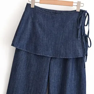 Detail van donkerblauwe denim rokbroek met zijstrikken