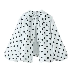 Detaillierte Vorderansicht der weißen Polka-Dot-Bluse mit großer dekorativer Halsschleife.