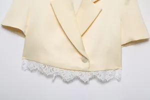 Close-up detail of cream cropped short sleeve blazer with elegant white lace hem