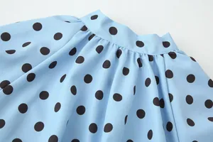 Detailaufnahme des gerafften Ausschnitts einer hellblauen gepunkteten Modebluse für Damen