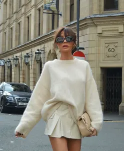 Professional street style view of a woman wearing an oversized white fuzzy mohair sweater