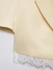 Detailed view of a cream short blazer featuring delicate white lace trim at the hem