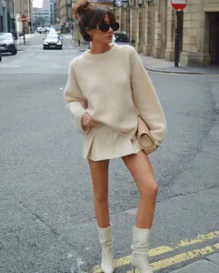 Street style model wearing cream fuzzy knit sweater with mini skirt and white boots.
