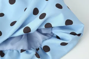 Makroaufnahme des hellblauen Stoffes mit klassischem schwarzen Punktmuster und feiner Textur.