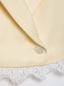 Close-up detail of pale yellow blazer with elegant white lace patchwork hemline