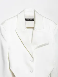 Primo piano di blazer in raso bianco con risvolto ed etichetta del marchio INDEFEIR