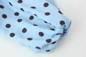 Nahaufnahme des elastischen Manschettendetails einer hellblauen Bluse mit schwarzen Punkten