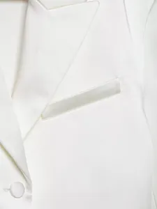 Dettaglio di un elegante blazer in raso bianco con risvolto a lancia e taschino
