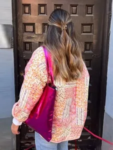 Rear view of a floral quilted jacket worn with a vibrant metallic pink tote bag
