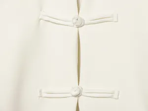 Nahaufnahme eines weißen Neckholder-Tops mit zarten handgefertigten Knotendetails
