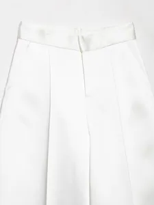 Dettaglio dei pantaloni bianchi in raso a vita alta che mostrano la consistenza del tessuto