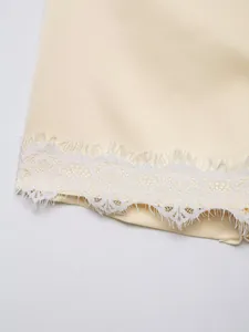 Close-up detail showing the delicate white eyelash lace trim on a cream garment hemline