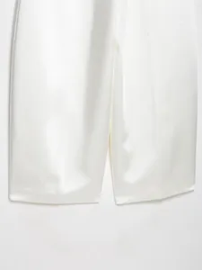 Primo piano di pantaloni a gamba larga in raso di seta bianco con orlo elegante
