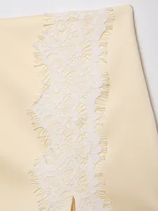 Close-up detail showing the intricate white lace splicing on a cream fabric garment