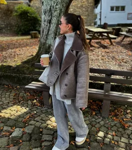 Fashionable woman wearing a lamb wool lapel shearling jacket in a cozy outdoor autumn setting.