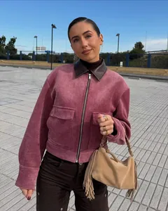 Stijlvol model in roze corduroy jas met bruine leren kraag en beige tas met franjes
