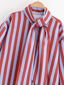 Vista detallada de una blusa de rayas rojas y azules con un lazo elegante en el cuello.