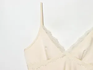Detailopname van de elegante V-hals met kant op een crèmekleurige zijden satijnen jurk.