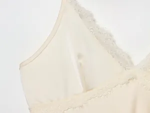 Macroweergave van delicaat kant en gladde satijnen stof op een crème camisole jurk