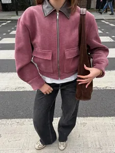Detailopname van een roze corduroy jas met bruine leren kraag in de straat.