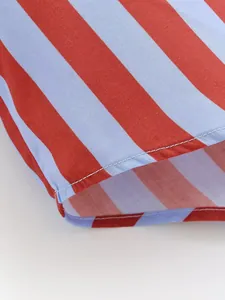 Vista detallada de la tela de camisa a rayas rojas y azul claro con costuras en el dobladillo.