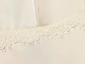 Detailopname van kanten rand op een crème satijnen slipjurk voor dames