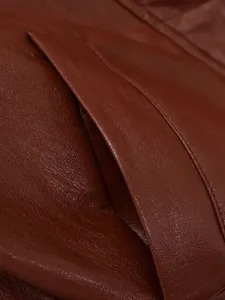 Gros plan détaillé de la poche d'une veste en cuir marron montrant les coutures et la texture