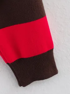 Detailed view of striped red and brown color block knitted sweater cuff texture.