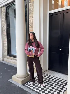 Modieuze vrouw die een roze corduroy jas met leren kraag draagt in een stedelijke omgeving