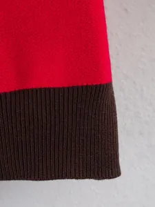 Close-up detail of the contrast ribbed cuff on a stylish red and brown knit sweater