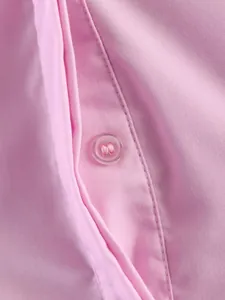 Vista dettagliata di un bottone in resina rosa e cuciture sottili su polo in cotone morbido